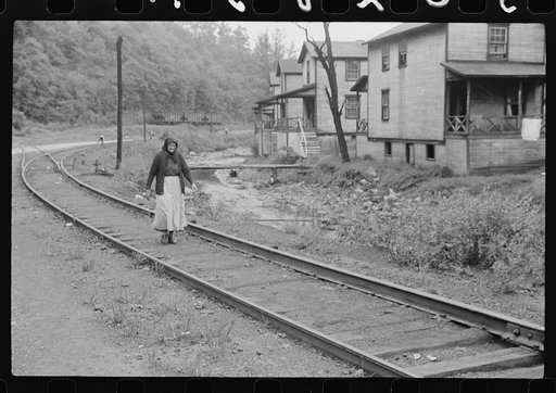 Untitled photo, possibly related to: Woman (probably Hungarian) coming home along railroad tracks in coal mining town, company houses at right, Pursglove, Scotts Run, West Virginia