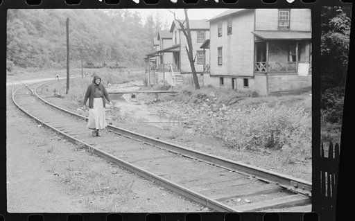 Untitled photo, possibly related to: Woman (probably Hungarian) coming home along railroad tracks in coal mining town, company houses at right, Pursglove, Scotts Run, West Virginia