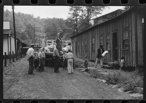 The relief truck brings food supplies to abandoned mining town, Jere, West Virginia. The shack on right is used as community house for prayer and church meetings, union and water company meetings, etc. Is represented by many people whose homes are so much worse than this