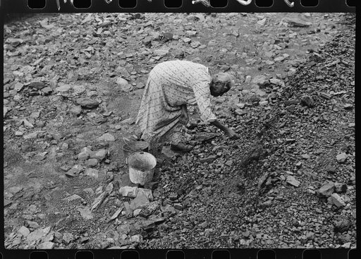 Negro woman picking up coal from old slate heaps in mining community. The "Patch," Cassville, West Virginia
