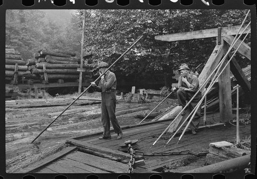 Untitled photo, possibly related to: Men spiking logs to go up ramp into sawmill. It was working only halftime and was even slower in winter.  "It's kinder hard them times. Concrete and steel's taking the place of lumber nowadays. Erwin, West Virginia