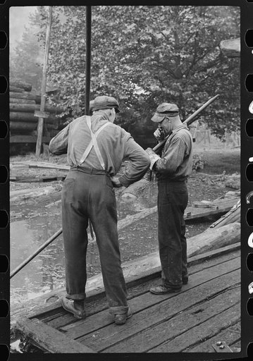 Untitled photo, possibly related to: Men spiking logs to go up ramp into sawmill. It was working only halftime and was even slower in winter.  "It's kinder hard them times. Concrete and steel's taking the place of lumber nowadays. Erwin, West Virginia