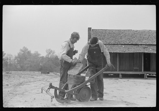 Mr. Ellis Adkins and his son, rural rehabilitation borrowers, examining new cultivator bought with FSA (Farm Security Administration) loan. There are nine in the family and this is their first year on the program. Coffee County, Alabama