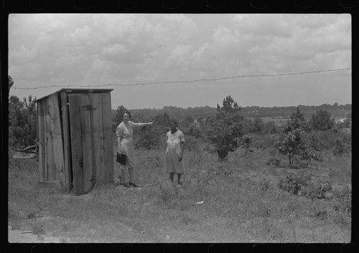 FSA (Farm Security Administration) home management supervisor pointing out to rehabilitation borrower where new privy will be located. Greene County, Georgia
