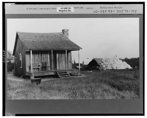 Sharecropper's house with cotton stacker against shed. Mississippi Delta, Mississippi