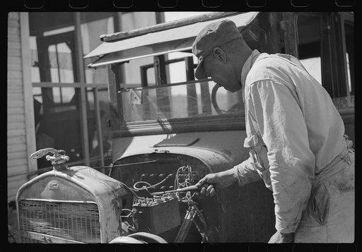 Uncle George who has worked on Marcella Plantation in blacksmith and carpentry shop for last fifty years after he got out of prison, fixing his old car, Mileston, Mississippi Delta, Mississippi