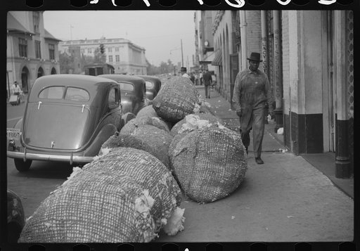 Cotton "snake," waste cotton on sidewalk, and cotton samples being carried to sampling and classing rooms in broker's office on Cotton Row, Front Street, Memphis, Tennessee