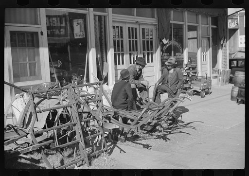 Farmers waiting around in front of farmer's supply company next to tobacco warehouse during auction sales, Durham, North Carolina