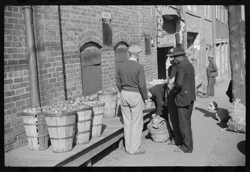 Untitled photo, possibly related to: Farmer having corn removed from his foot on street outside tobacco warehouse during auction sales, Durham, North Carolina