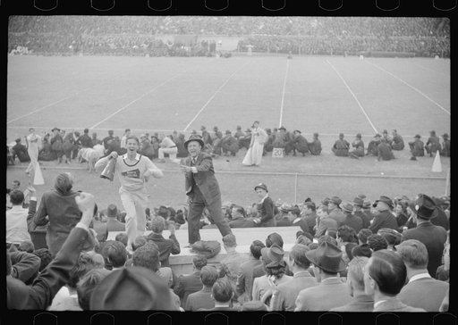 Kay Kyser and cheerleader cheering for North Carolina team at Duke University-North Carolina football game. Durham, North Carolina