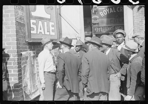 Patent medicine salesman talking to farmers outside warehouse during tobacco auction sales. Durham, North Carolina