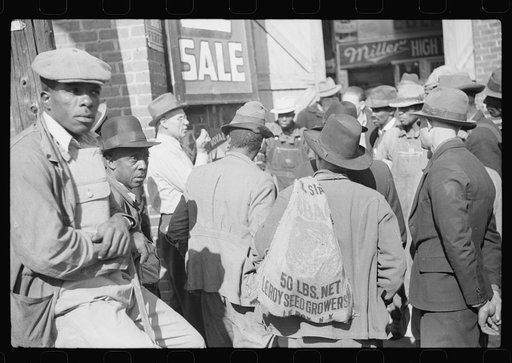 Patent medicine salesman demonstrating his wares to farmers outside warehouse during tobacco auction sale. Durham, North Carolina