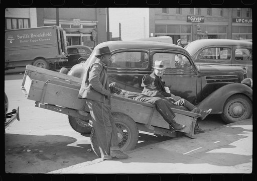 Farmers waiting around outside warehouse before tobacco auction sale.  Tobacco was brought in trailer to warehouse. Oxford, North Carolina