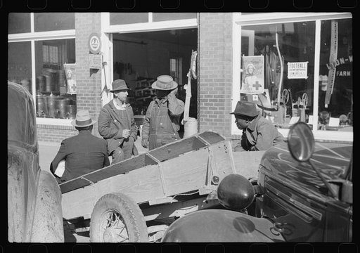 Farmers waiting around outside warehouse before tobacco auction sale.  Tobacco was brought in trailer to warehouse. Oxford, North Carolina