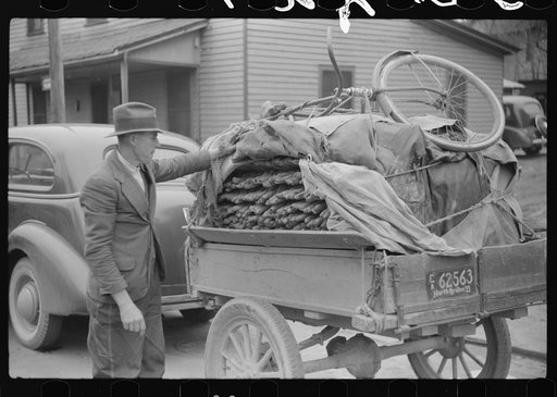 Mr. Wilkins with trailer full of tobacco which he has brought to be auctioned at warehouse. On top of load is his son's bicycle which he brought to town to be repaired. Durham, North Carolina