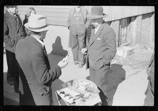 Untitled photo, possibly related to: Salesman displaying patent medicine to farmers who have brought tobacco to warehouse and are waiting outside for the sales to begin. Mebane, North Carolina