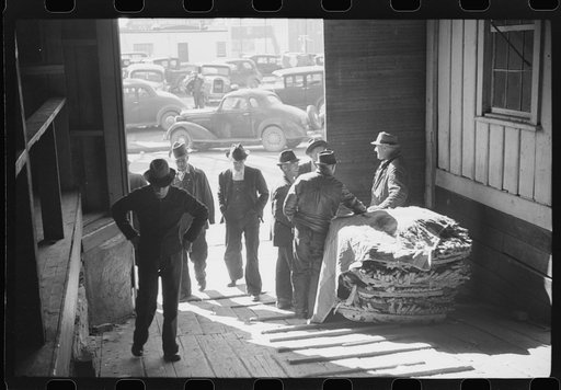Untitled photo, possibly related to: Arranging tobacco in baskets before auction sale in warehouse. Mebane, North Carolina