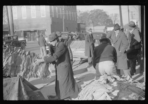Untitled photo, possibly related to: Farmers and warehousemen unloading tobacco on sidewalk, before auction sale. The warehouse was too overloaded to permit more tobacco being brought in. Mebane, North Carolina