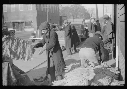 Untitled photo, possibly related to: Farmers and warehousemen unloading tobacco on sidewalk, before auction sale. The warehouse was too overloaded to permit more tobacco being brought in. Mebane, North Carolina