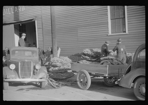 Farmers and warehousemen unloading tobacco on sidewalk before auction sales. The warehouse was too overloaded to permit more tobacco being brought in. Mebane County, North Carolina