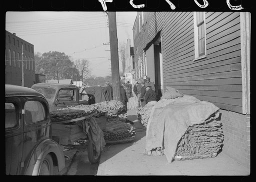 Untitled photo, possibly related to: Farmers and warehousemen unloading tobacco on sidewalk, before auction sale. The warehouse was too overloaded to permit more tobacco being brought in. Mebane, North Carolina