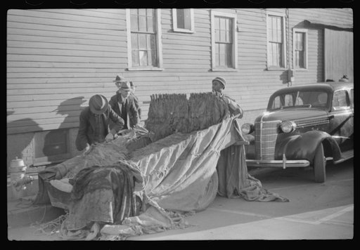 Untitled photo, possibly related to: Farmers and warehousemen unloading tobacco on sidewalk, before auction sale. The warehouse was too overloaded to permit more tobacco being brought in. Mebane, North Carolina