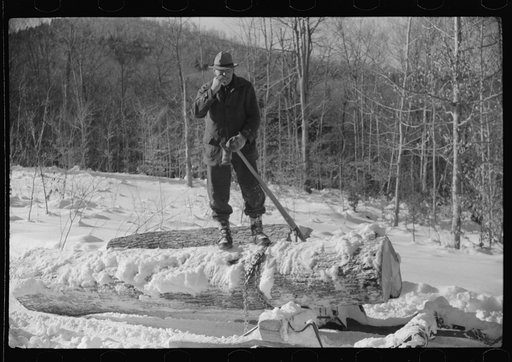 Log being hauled by a tractor from woods to the road, where it will be loaded on a truck and taken to sawmill. Near Barnard, Vermont