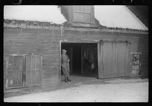 Hired man in doorway of barn on Putney Homestead near Woodstock, Vermont