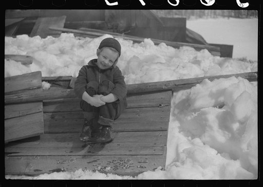 Young daughter of Frank H. Shurtleff sitting outside sugar house where sap from maple trees is boiled down into maple syrup. The Shurtleff farm has about 400 acres, and was originally purchased by grandfather in 1840. He raises sheep, cows, cuts lumber and has been making maple syrup for about thirt