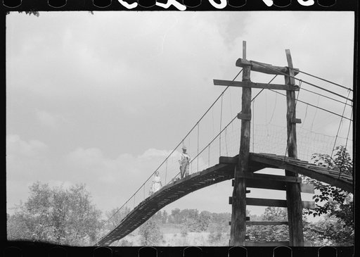 Mountaineers crossing the Kentucky River over swinging bridge, carrying their supplies home from Jackson. Breathitt County, Kentucky