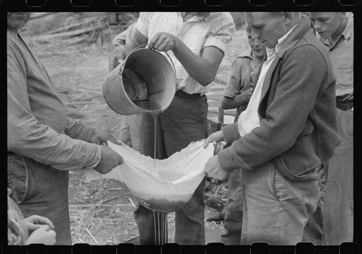 Pouring off and straining finished sorghum syrup after it had been boiled down at a "syruping off" on the highway between Jackson and Campton, Kentucky
