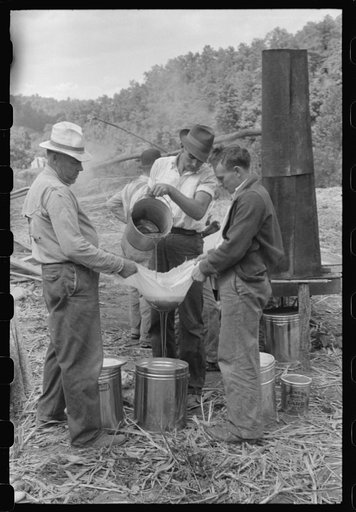 Untitled photo, possibly related to: Pouring off and straining finished sorghum syrup after it had been boiled down at a "syruping off" on the highway between Jackson and Campton, Kentucky