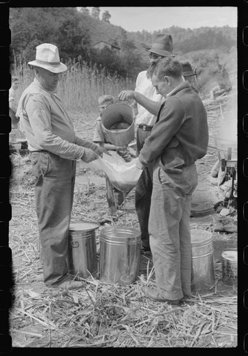 Pouring off and straining finished sorghum syrup after it had been boiled down at a "syruping off" on the highway between Jackson and Campton, Kentucky