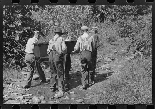Mountain people carrying a homemade coffin up creek bed to the family plot on the hillside where it will be buried. This section is too isolated to hold any formal funeral services immediately. Up South Fork of the Kentucky River near Jackson, Kentucky