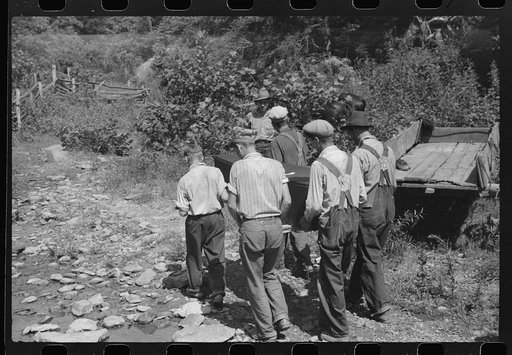 Mountain people carrying a homemade coffin up creek bed to the family plot on the hillside where it will be buried. This section is too isolated to hold any formal funeral services immediately. Up South Fork of the Kentucky River near Jackson, Kentucky