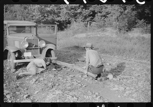Untitled photo, possibly related to: Mountaineer and Marion Post Wolcott changing a tire with a fence post as a jack. Up South Fork of the Kentucky River. Kentucky