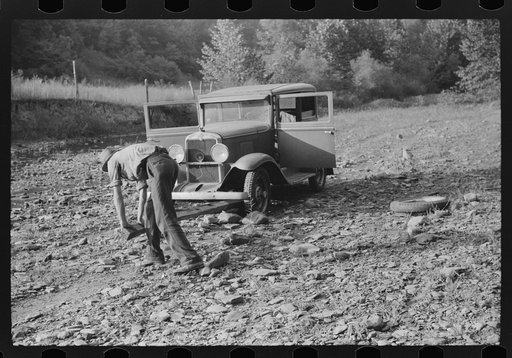 Mountaineer trying to change tire with a fence post as a jack. Up South fork of the Kentucky River. Breathitt County, Kentucky