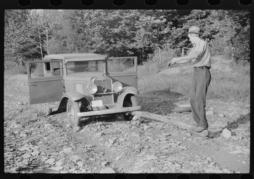 Mountaineer trying to change tire with a fence post as a jack. Up South fork of the Kentucky River. Breathitt County, Kentucky