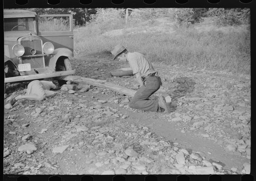 Mountaineer and Marion Post Wolcott changing a tire with a fence post as a jack. Up South Fork of the Kentucky River. Kentucky