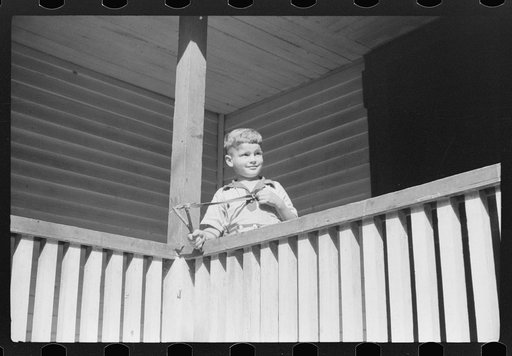 Mountain child shooting slingshot from porch of his home. Near Buckhorn, Kentucky