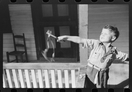 Mountain child shooting slingshot from porch of his home. Near Buckhorn, Kentucky