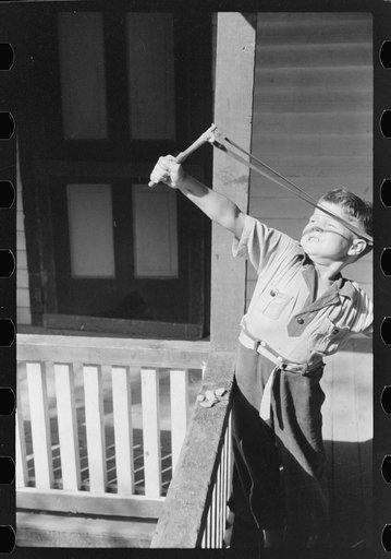 Untitled photo, possibly related to: Mountain child shooting slingshot from porch of his home. Near Buckhorn, Kentucky