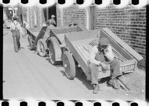 Untitled photo, possibly related to: Farmers' trailers with tobacco sticks outside of warehouse during auction sale. Danville, Virginia
