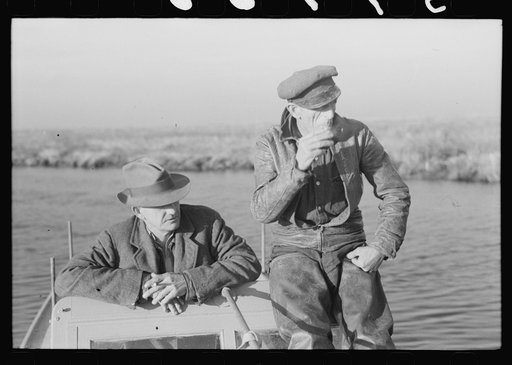 Untitled photo, possibly related to: Spanish trapper talking to his helper about the scarcity of muskrats this year because of the flood and adverse weather conditions. In the marshland near Delacroix Island, Louisiana