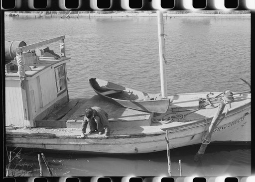 Untitled photo, possibly related to: Spanish trapper's son repairing their boat which is used to go out to their camps in the marshes and for fishing and shrimping in other seasons. On Delacroix Island, Louisiana