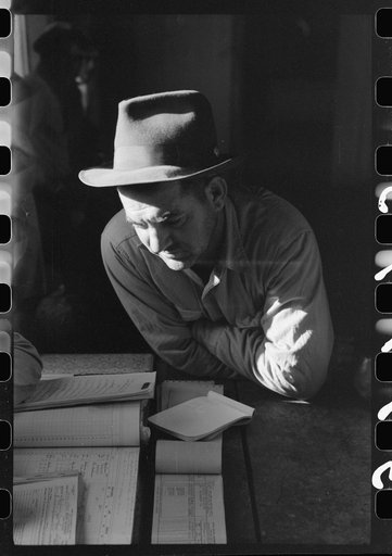 Untitled photo, possibly related to: Fur buyer from New Orleans waiting for FSA (Farm Security Administration) supervisor to open the bids at auction sale of muskrats in dancehall on Delacroix Island,  Louisiana
