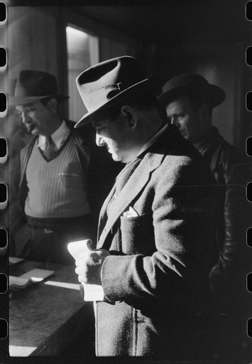 Fur buyer from New Orleans waiting for FSA (Farm Security Administration) supervisor to open the bids at auction sale of muskrats in dancehall on Delacroix Island, Louisiana. See general caption no. 1