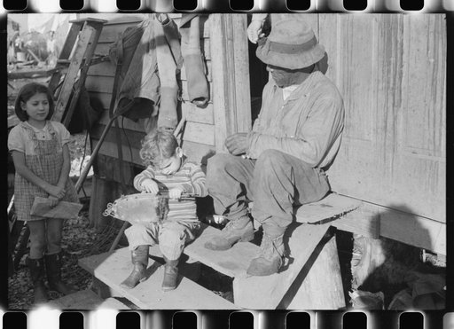 Spanish muskrat trapper's son with stretched skins in his hands. In back of their camp in the marshes on Delacroix Island, Louisiana. See general caption no. 1
