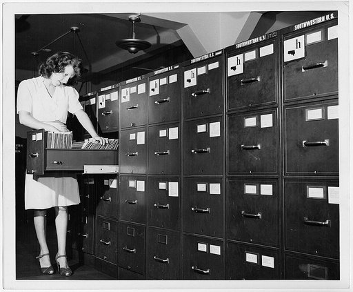Jeannette Poirier looking at photographs in file cabinet drawer at the Washington office of the Overseas Branch of the U.S. Office of War information
