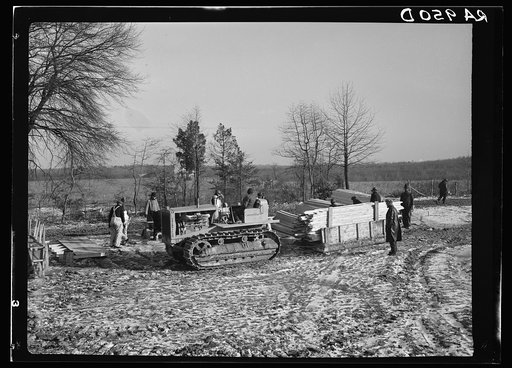 Wooden sleds drawn by tractor bringing supplies from main road to project at Berwyn, Maryland. During the winter months tractors and mud sleds furnish the only method of getting from the main road to the project. Transportation was chief problem at the new construction